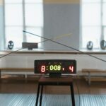Two fencers engaged in a duel with the scoreboard showing 8:4 indoors.