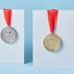 Gold and silver medals with red ribbons against a blue backdrop representing achievement and success.
