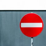 A red and white no entry sign against a blue wall, symbolizing prohibition.