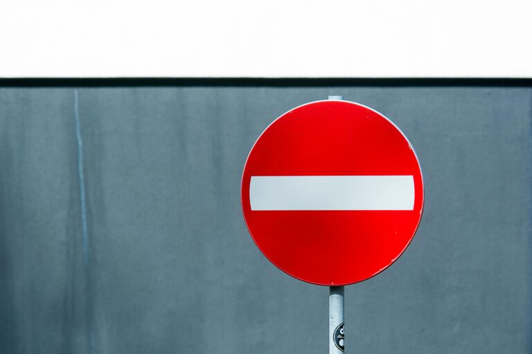 A red and white no entry sign against a blue wall, symbolizing prohibition.
